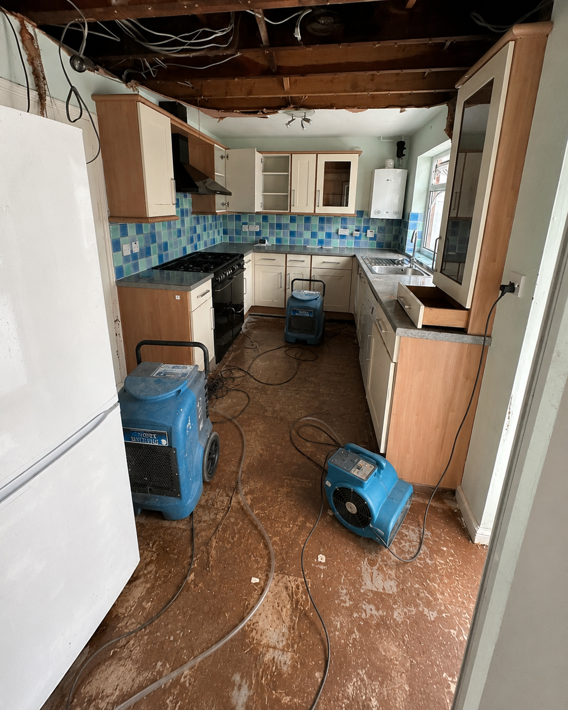 Kitchen drying setup with dehumidifier and air movers positioned around the room